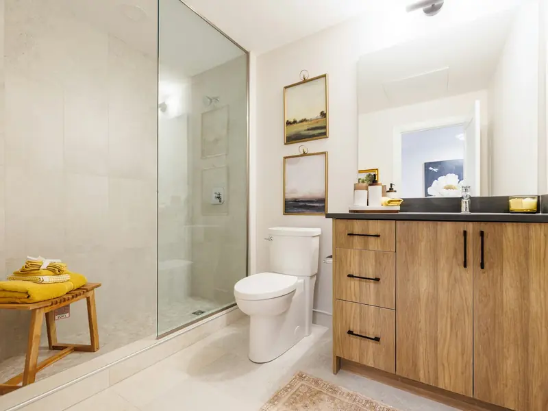 Clean bathroom with clear glass shower and wood vanity