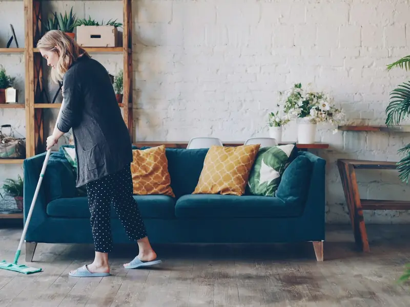 Cleaner mopping the floor of a tidy living room